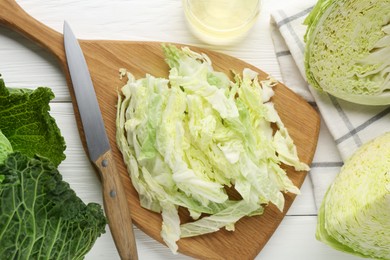 Photo of Fresh cut Savoy cabbage and knife on white table, flat lay