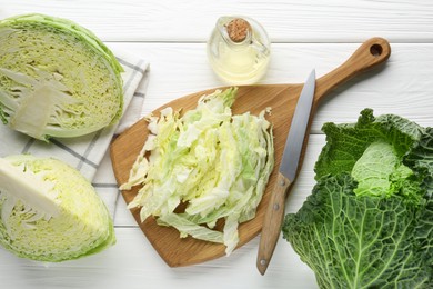 Photo of Fresh cut Savoy cabbage and knife on white table, flat lay