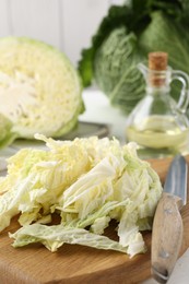 Photo of Fresh cut Savoy cabbage and knife on white table, closeup