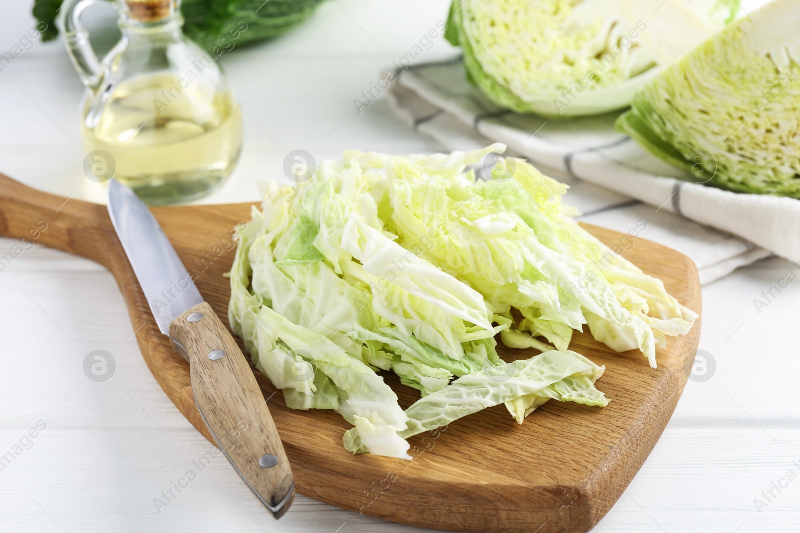 Photo of Fresh cut Savoy cabbage and knife on white wooden table, closeup