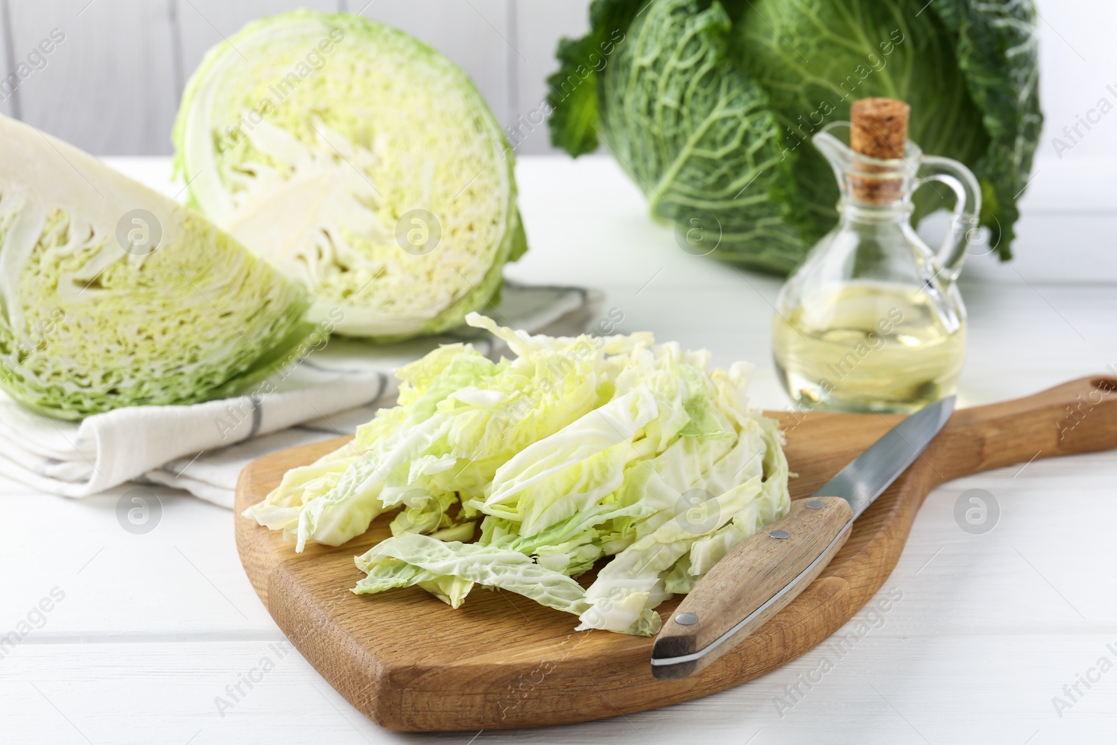 Photo of Fresh cut Savoy cabbage and knife on white wooden table, closeup