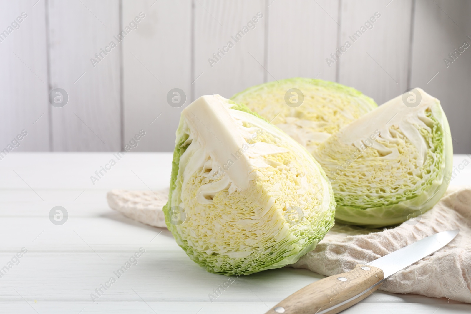 Photo of Fresh cut Savoy cabbage and knife on white wooden table, closeup. Space for text