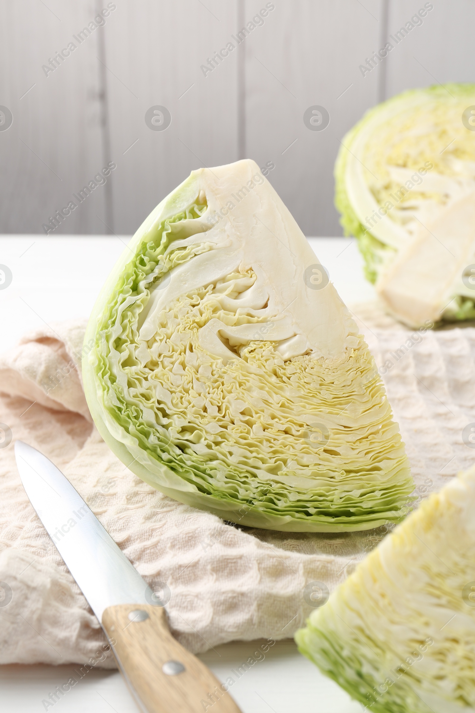 Photo of Fresh cut Savoy cabbage and knife on white wooden table, closeup