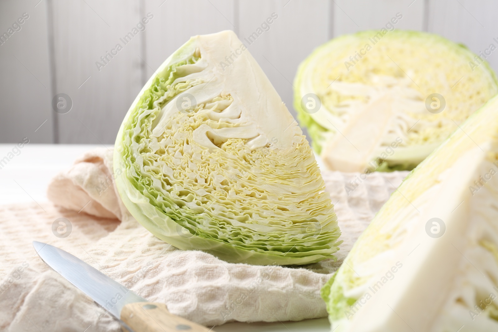 Photo of Fresh cut Savoy cabbage and knife on table, closeup