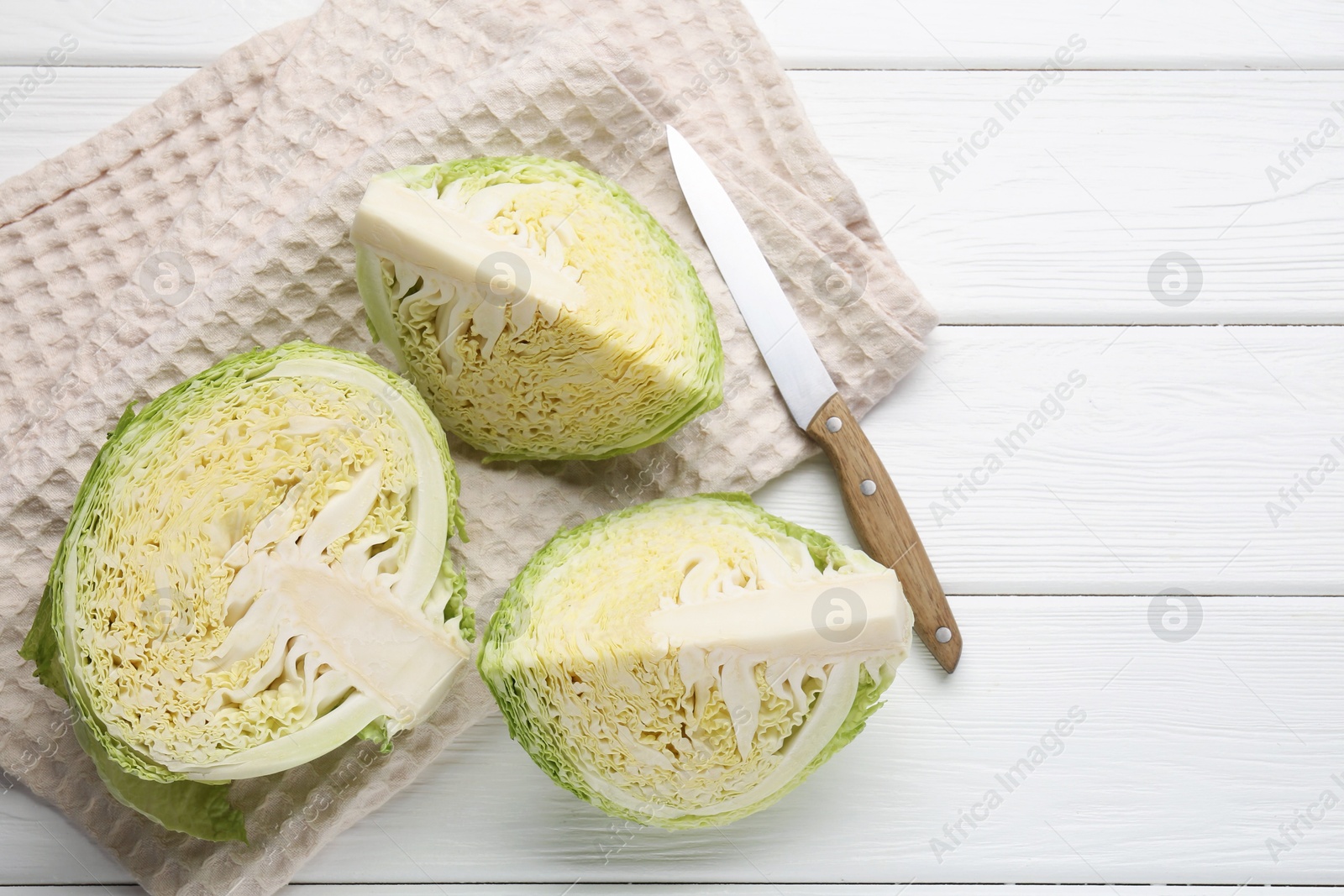 Photo of Fresh cut Savoy cabbage and knife on white wooden table, flat lay. Space for text