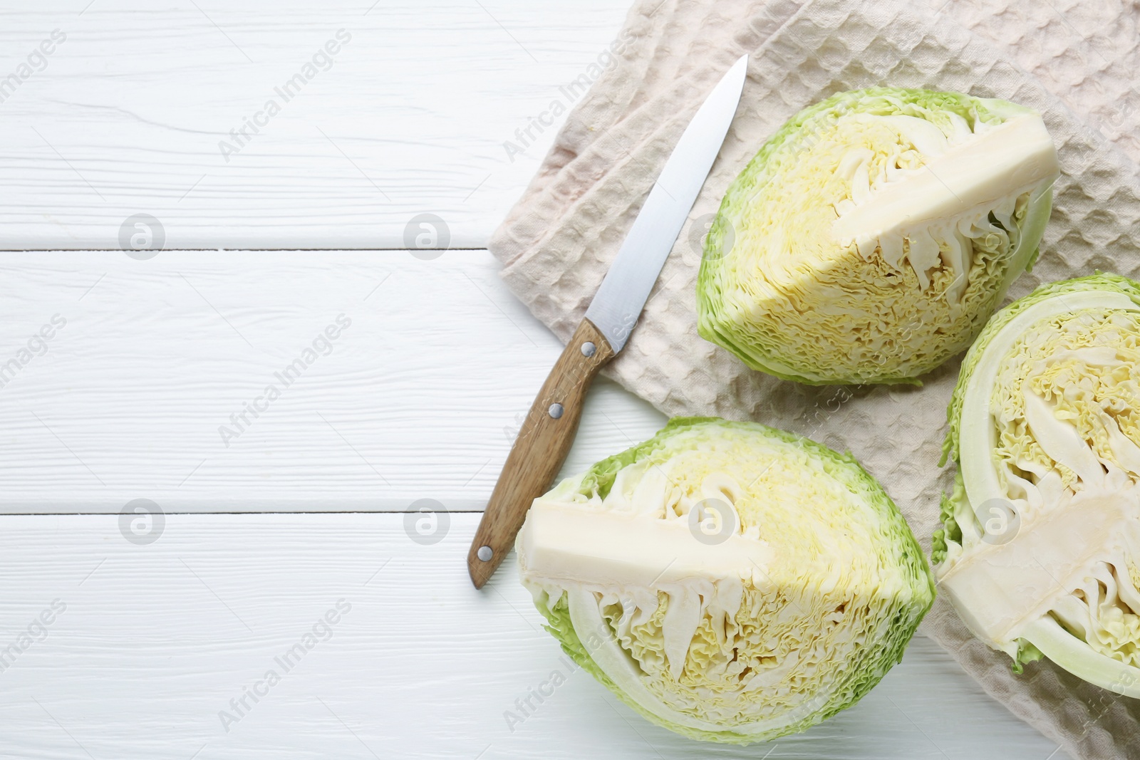Photo of Fresh cut Savoy cabbage and knife on white wooden table, flat lay. Space for text