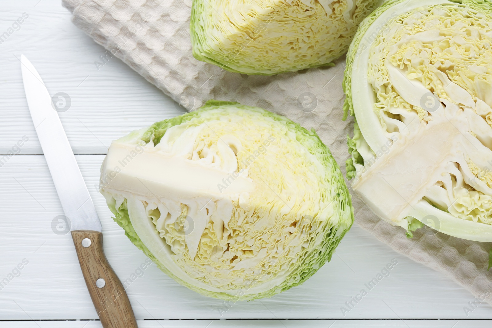 Photo of Fresh cut Savoy cabbage and knife on white wooden table, flat lay