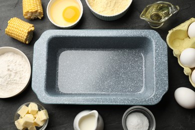 Photo of Cornbread preparation. Baking dish surrounded by different ingredients on black textured table, flat lay
