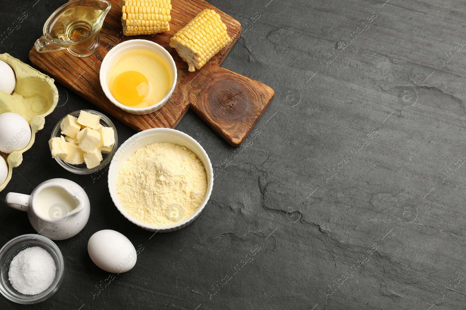 Photo of Cornbread preparation. Different ingredients on black textured table, flat lay. Space for text