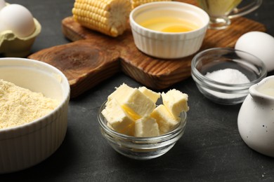 Photo of Making cornbread. Different ingredients on black textured table, closeup