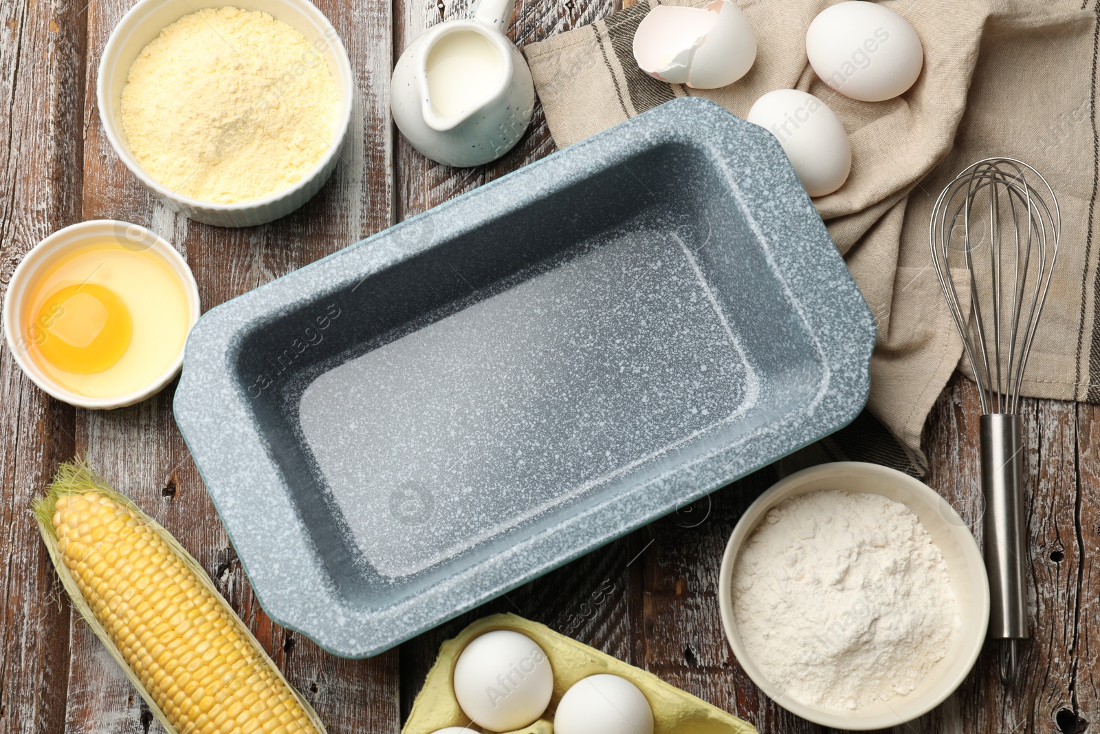 Photo of Making cornbread. Baking dish, different ingredients and whisk on wooden table, flat lay