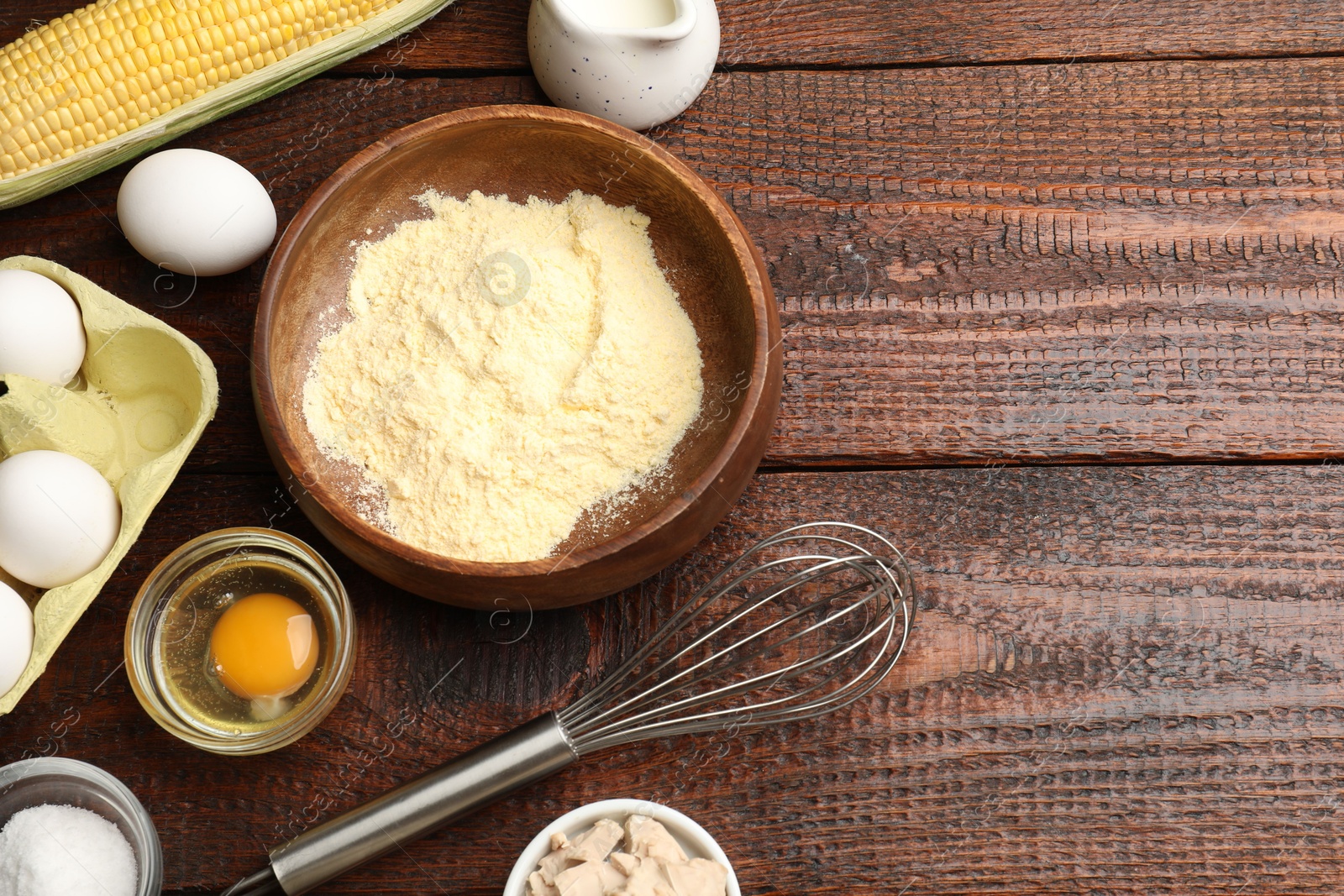 Photo of Making cornbread. Different ingredients and metal whisk on wooden table, flat lay. Space for text