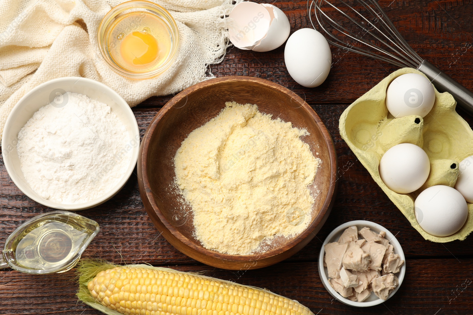 Photo of Making cornbread. Different ingredients and metal whisk on wooden table, flat lay