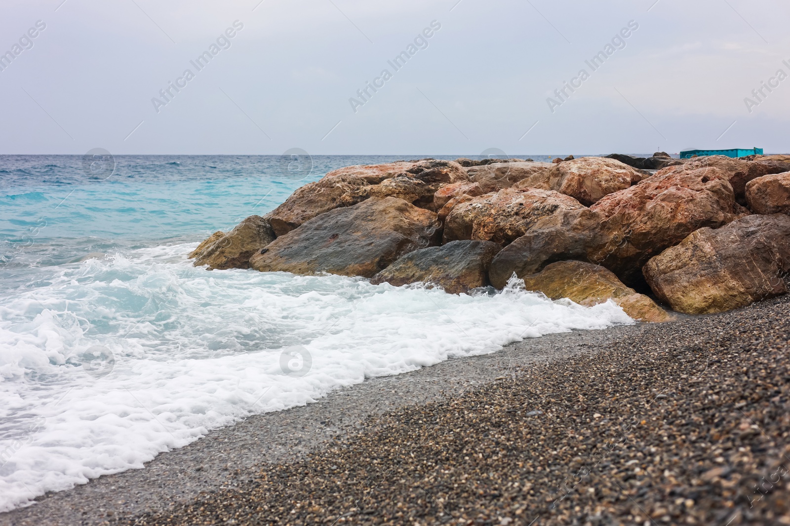 Photo of Beautiful view of wavy sea, rocks and pebbles on beach