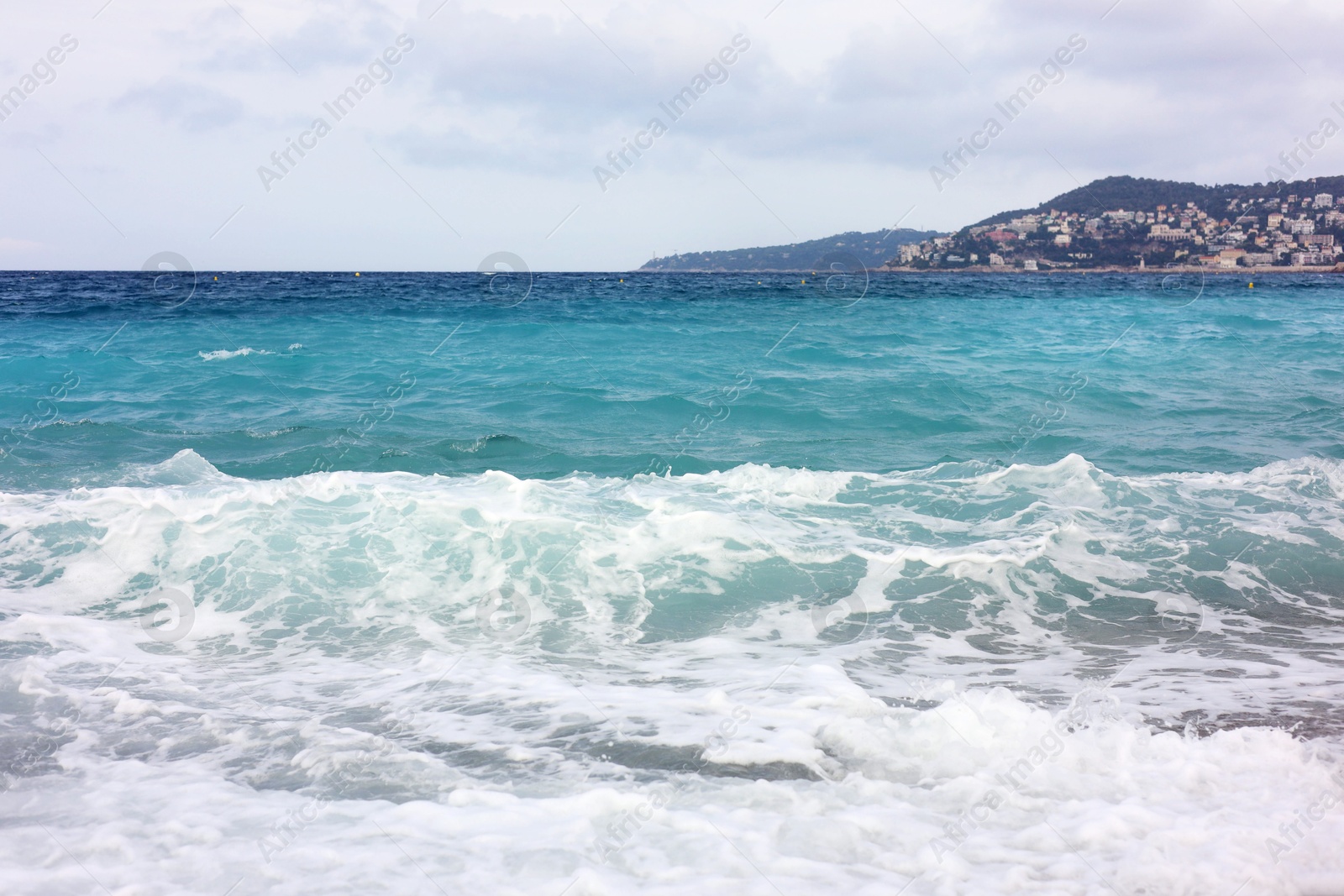 Photo of Beautiful view of wavy sea, city and pebbles on beach