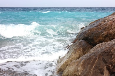 Photo of Beautiful view of wavy sea, rocks and pebbles on beach