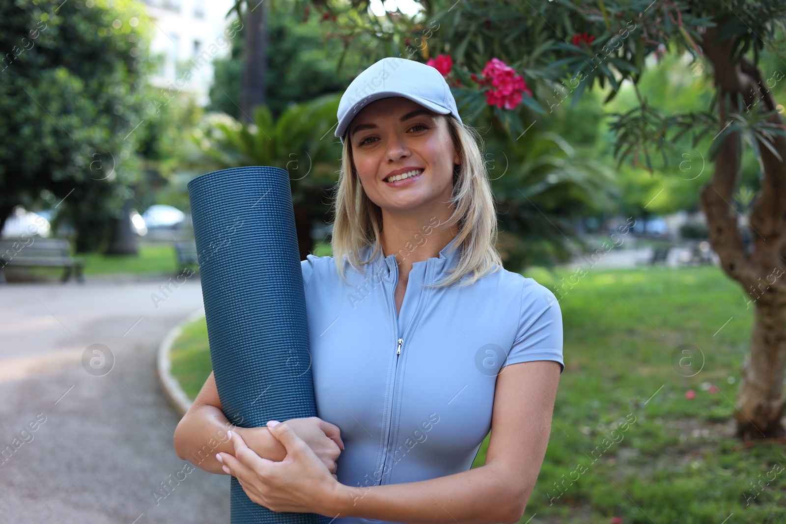 Photo of Happy young woman with yoga mat outdoors