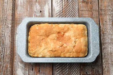 Photo of Freshly baked cornbread in baking dish on color wooden table, top view