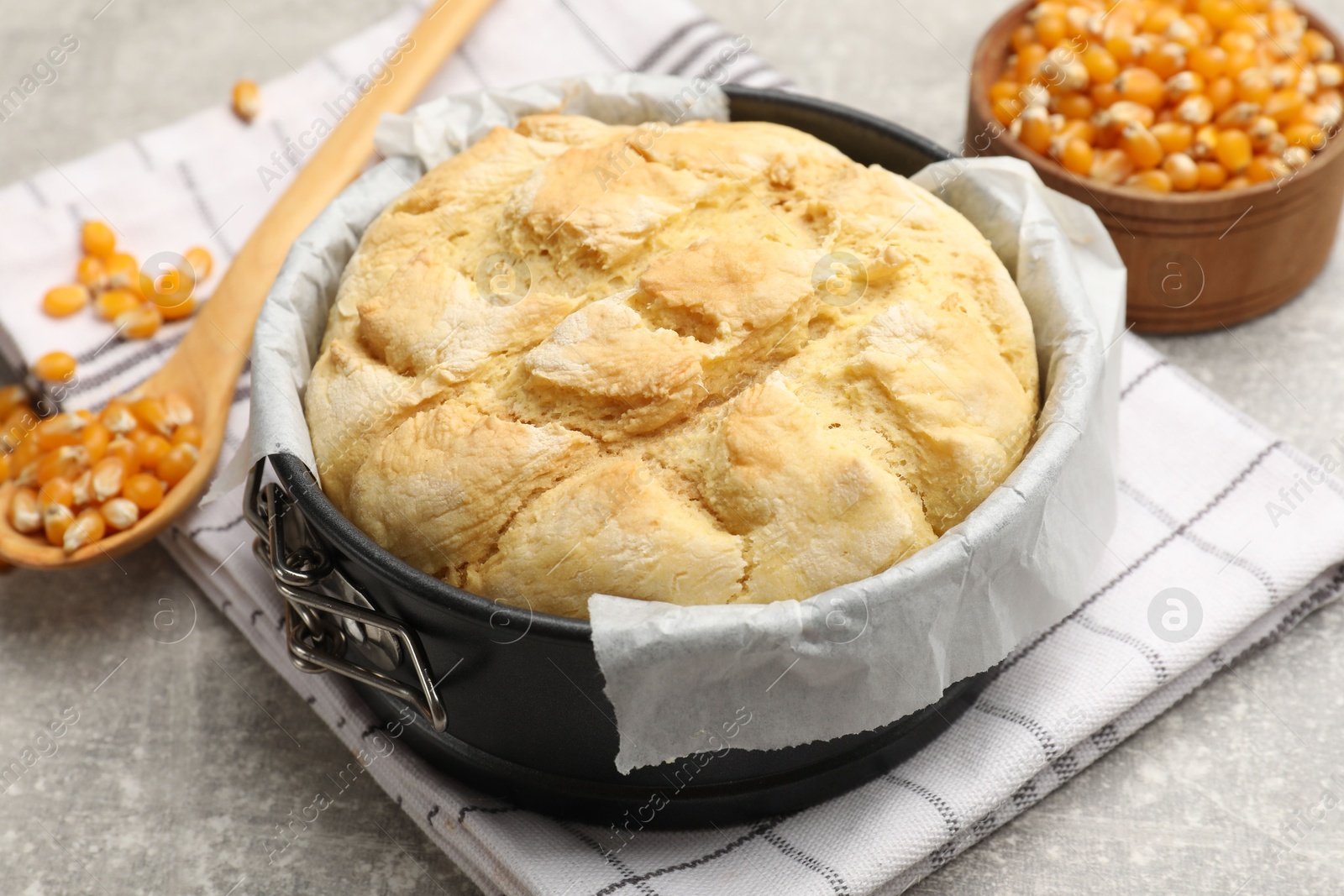 Freshly baked cornbread in cake pan, seeds and spoon on grey textured table, closeup Photo of Freshly baked cornbread in cake pan, seeds and spoon on grey textured table, closeup