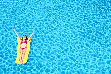 Image of Young woman on inflatable mattress in swimming pool, above view