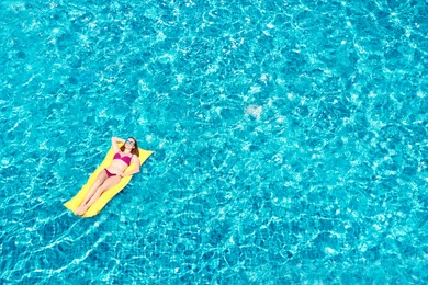 Image of Young woman on inflatable mattress in swimming pool, above view