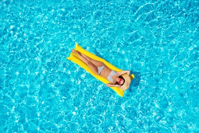 Image of Young woman with inflatable mattress in swimming pool, top view