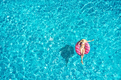 Image of Young woman with inflatable ring in swimming pool, top view. Summer vacation
