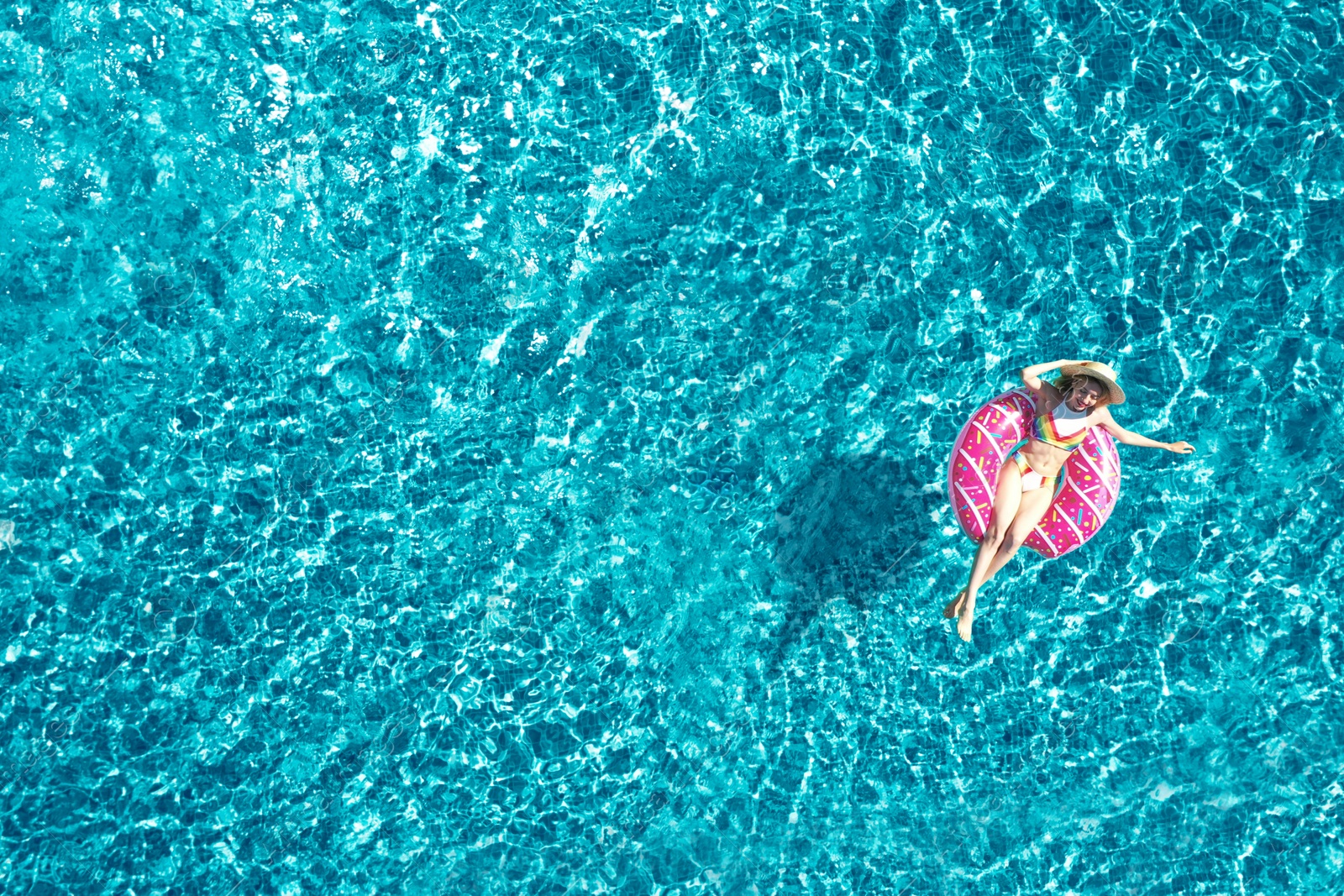 Image of Young woman with inflatable ring in swimming pool, top view. Summer vacation