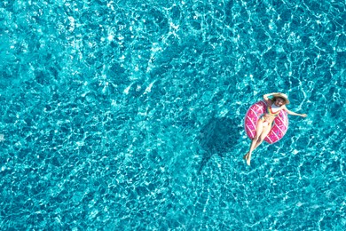 Image of Young woman with inflatable ring in swimming pool, top view. Summer vacation