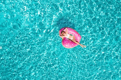 Image of Young happy woman with inflatable ring in swimming pool, top view. Summer vacation