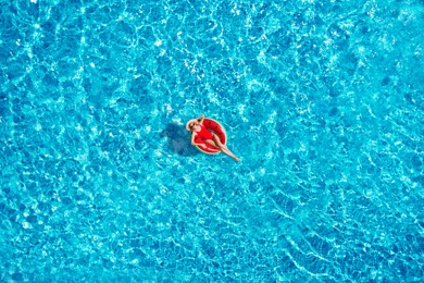 Image of Young happy woman with inflatable ring in swimming pool, top view. Summer vacation