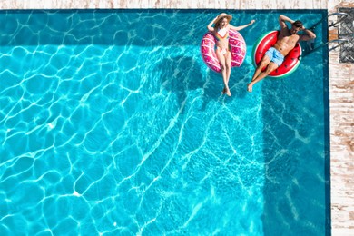 Image of Happy couple with inflatable rings in swimming pool, top view. Summer vacation
