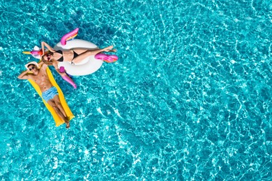 Image of Happy couple with inflatable ring and mattress in swimming pool, top view. Summer vacation