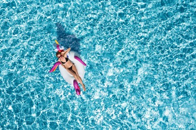 Image of Young happy woman with inflatable ring in swimming pool, top view. Summer vacation
