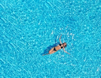 Image of Beautiful young woman swimming in pool, top view