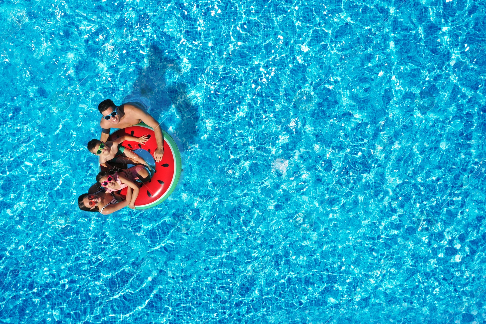 Image of Happy family with inflatable ring in swimming pool, top view. Summer vacation