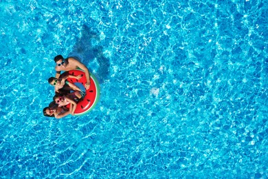 Image of Happy family with inflatable ring in swimming pool, top view. Summer vacation