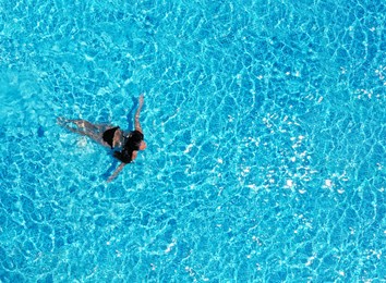 Image of Beautiful young woman swimming in pool, top view. Space for text