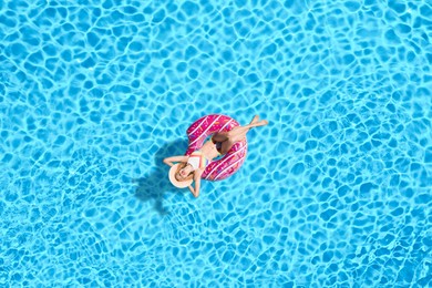 Image of Young happy woman with inflatable ring in swimming pool, top view. Summer vacation