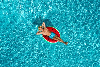 Image of Happy man with inflatable ring in swimming pool, top view. Summer vacation