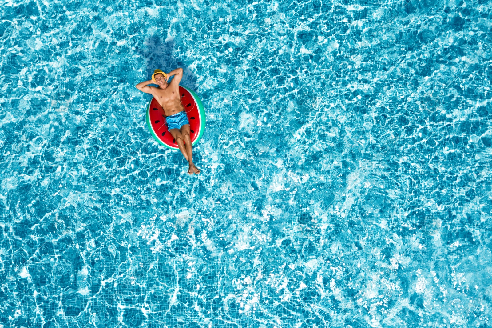 Image of Happy man with inflatable ring in swimming pool, top view. Summer vacation