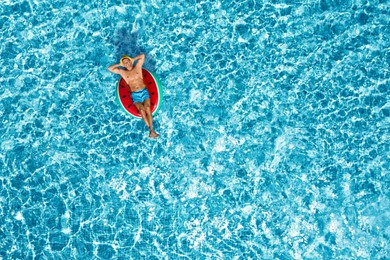 Image of Happy man with inflatable ring in swimming pool, top view. Summer vacation