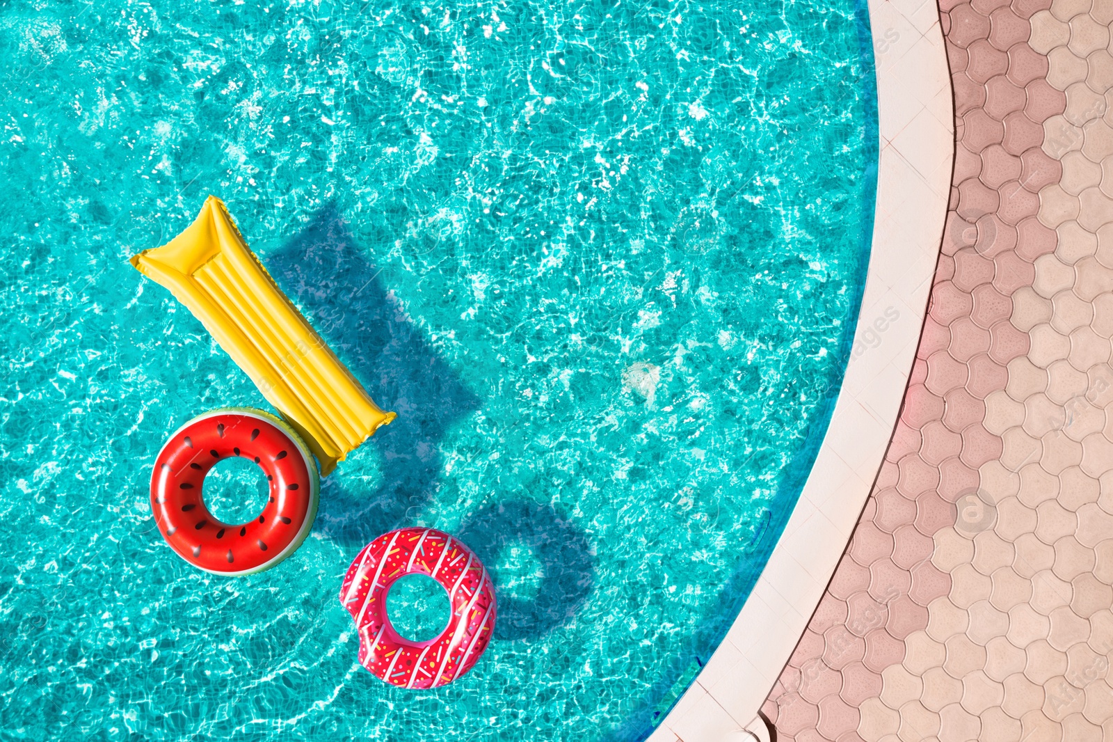 Image of Inflatable rings and mattress floating in swimming pool, top view. Summer vacation