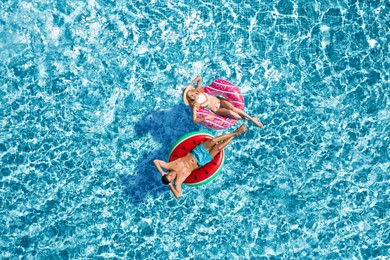 Image of Happy couple with inflatable rings in swimming pool, top view. Summer vacation