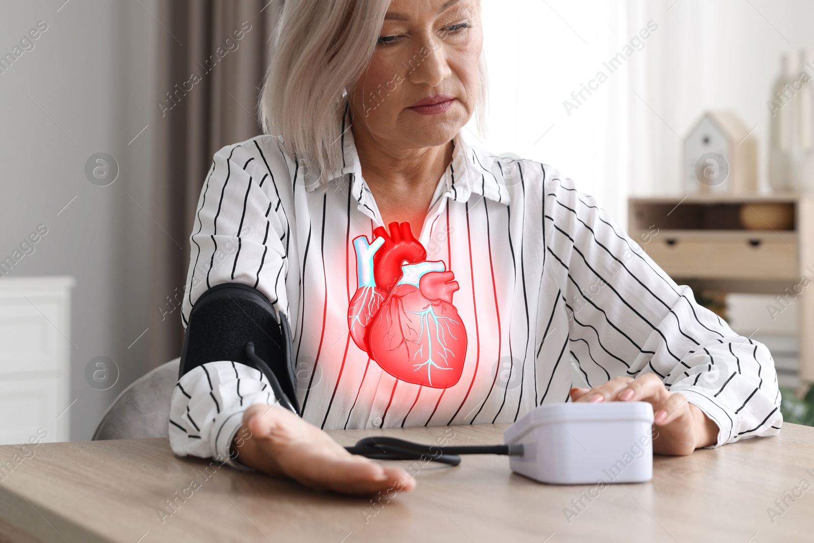 Image of Cardiology. Senior woman measuring blood pressure at table indoors, closeup. Illustration of heart on her chest