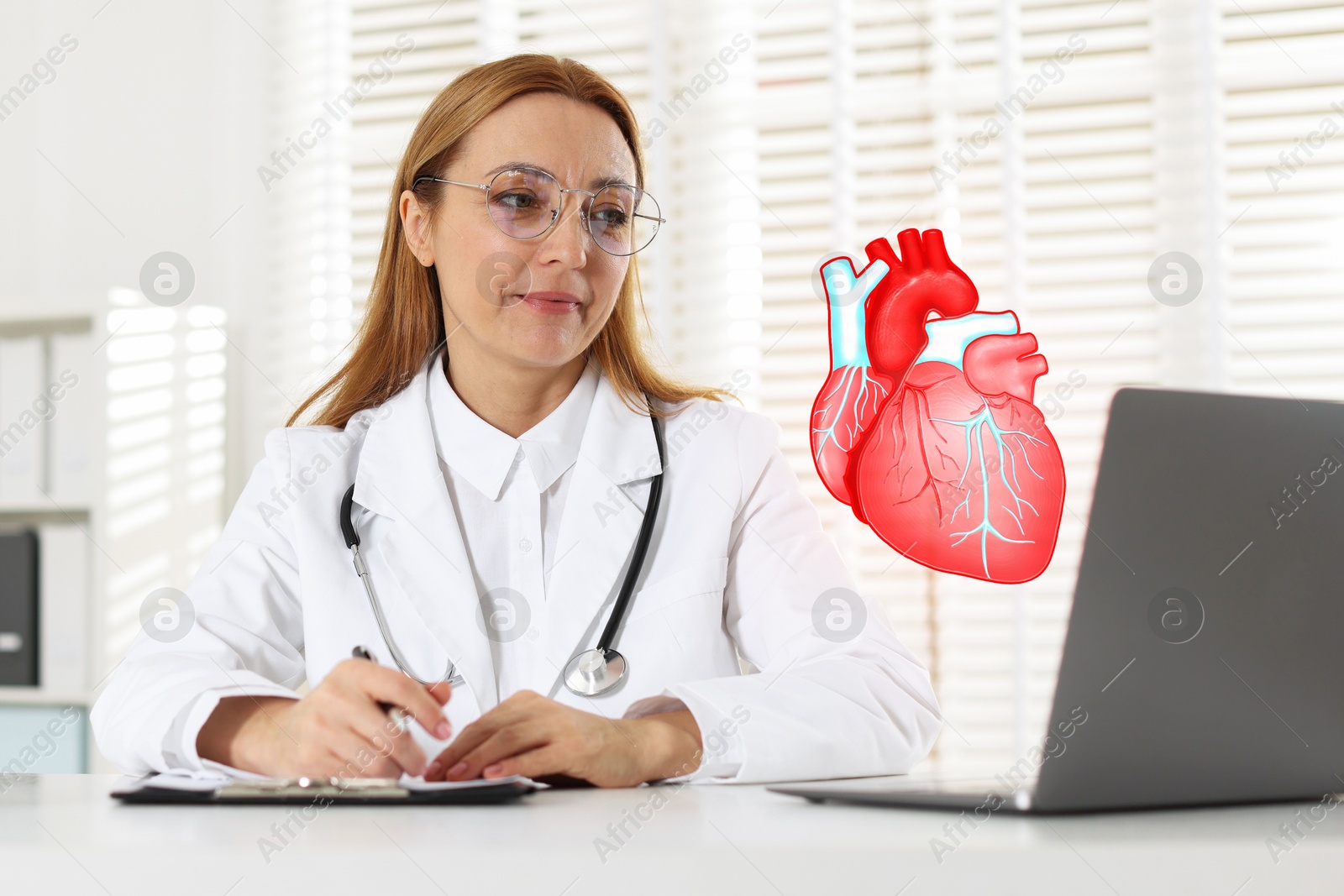 Image of Cardiologist with stethoscope working at white table in clinic. Illustration of heart above laptop