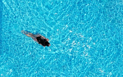 Image of Beautiful young woman swimming in pool, top view
