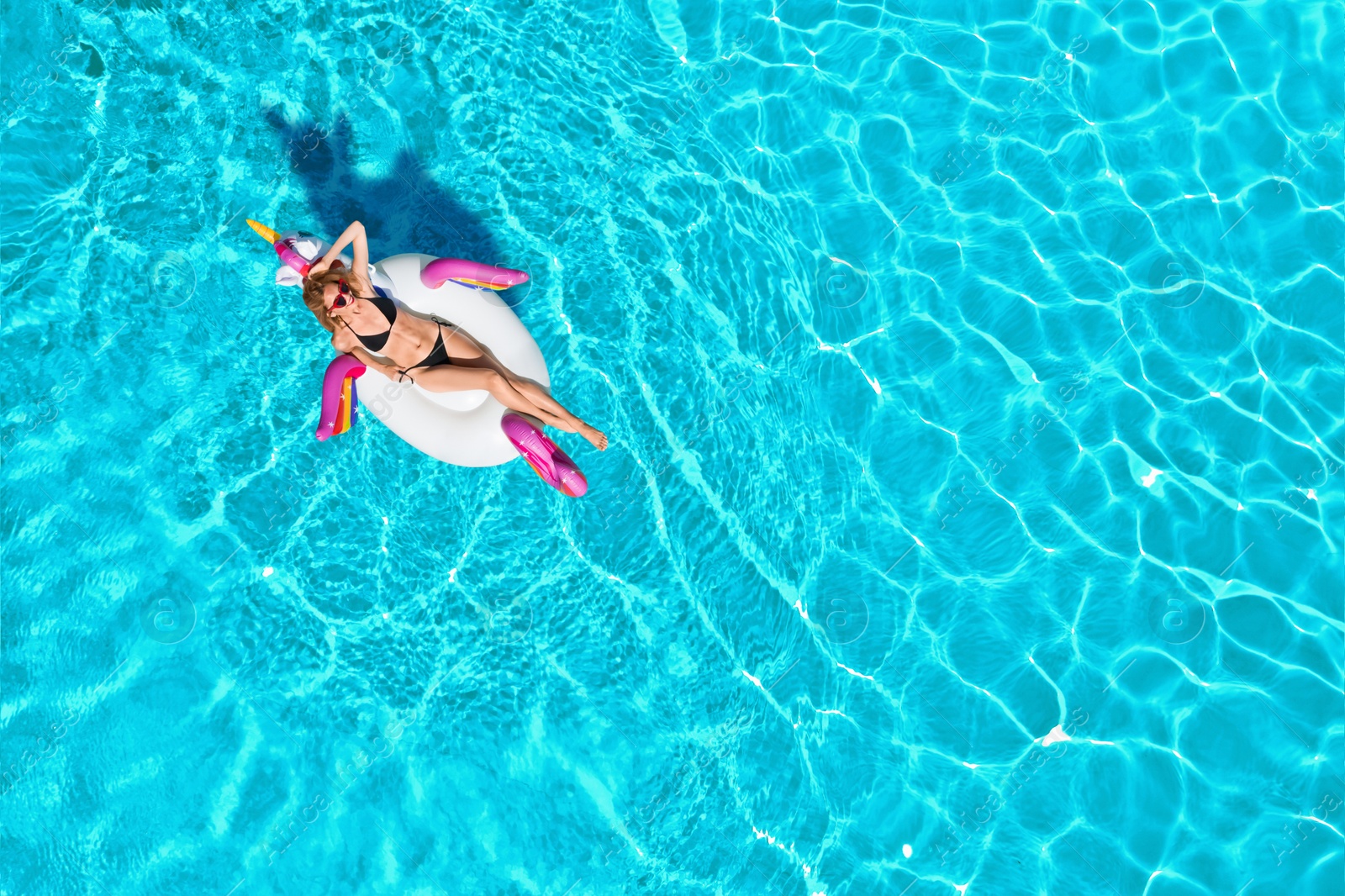 Image of Young happy woman with inflatable ring in swimming pool, top view. Summer vacation