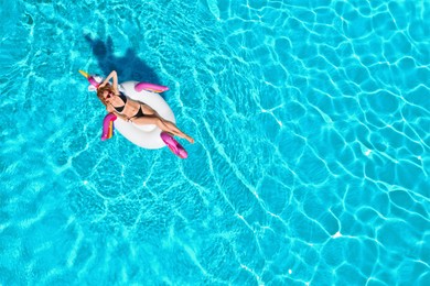 Image of Young happy woman with inflatable ring in swimming pool, top view. Summer vacation