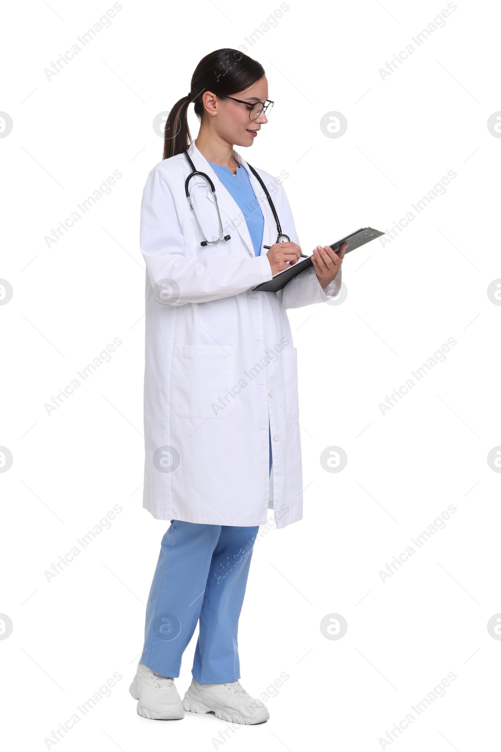 Smiling doctor in uniform, stethoscope and glasses writing on clipboard against white background Photo of Smiling doctor in uniform, stethoscope and glasses writing on clipboard against white background